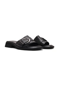 Sandalias deslizantes de cuero negro con una tira ancha que presenta una hebilla en tono plateado. Tacón bajo, diseño de punta abierta, textura suave.