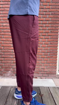 Vijolične športne hlače s tanko zasnovo, narejene iz lahkega materiala. Imajo zadrge na gležnjih in bočne žepe. Nošene z modrimi supergami.