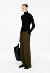 Black long-sleeve turtleneck shirt, olive wide-leg trousers, and a glossy black tote bag; sleek silhouette and casual design.