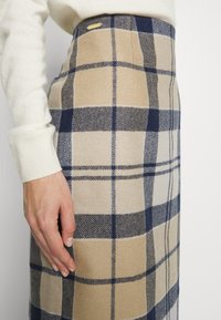 Kokerrok tot op de knie in een beige en marineblauw ruitpatroon; gemaakt van geweven stof met een getextureerde afwerking; voorzien van een kleine gouden accent.