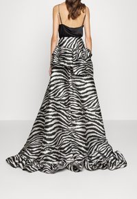 Svart och vit zebra-randig klänning med en satinkorsett, rynkad midja och en flödande kjol som sträcker sig ner till golvet med en rynkad nederkant.
