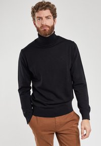 Maglione a dolcevita nero realizzato in un materiale a maglia liscia. Presenta maniche lunghe e dettagli a costine sul colletto e sull'orlo.