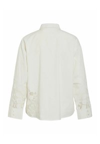 Balts garu piedurkņu krekls ar ziedu izšuvumiem uz piedurknēm, pielāgotu apkakli un pogu aprocēm. Gluda, viegla auduma.