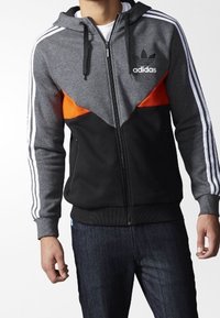 Chaqueta con capucha gris y negra con detalles en naranja, tres rayas blancas en las mangas y un logo de Adidas en el pecho. Tejido suave.