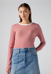 Långärmad röd och vit randig bomullsskjorta med rundad halsringning, tillsammans med en hög midja blå jeanskjol med framseam.