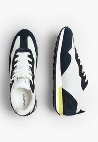 Sneaker navy e bianche con materiali in suede e mesh, dotate di una suola bianca con un accento giallo e chiusura con lacci.
