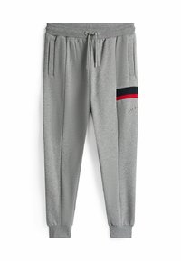 Pantalones jogger grises fabricados en tejido suave, con cintura ajustable mediante cordón, bolsillos laterales y un detalle de rayas rojas y azul marino.