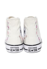 Sneakers alte in tela bianca con ricami floreali in rosa e verde. Suola in gomma nera con branding "Converse All Star" sul tallone.