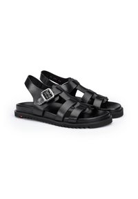 Schwarze Ledersandalen mit gekreuzten Riemen, offenem Rücken und verstellbarem Schnallenverschluss, ausgestattet mit einer strukturierten, geriffelten Sohle.