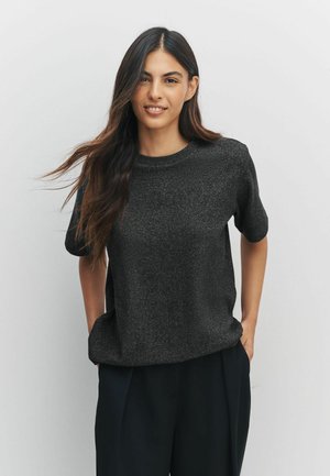 Schwarzes Kurzarmhemd mit strukturierter Oberfläche, Rundhalsausschnitt und lässigem Schnitt, kombiniert mit dunklen Hosen. Einfaches, modernes Design.