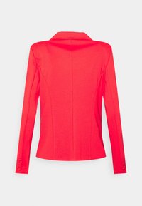 Blazer rojo de manga larga con solapa, corte entallado, textura suave y detalles de botones en los puños. Vista trasera, fondo liso.