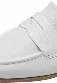 Scarpa bianca in pelle con una texture liscia, caratterizzata da una larga cinghia sulla parte superiore e un design con punta arrotondata. Parte della suola è marrone chiaro.