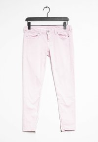 Jeans skinny de algodón rosa exhibidos en una percha negra, que cuentan con bolsillos frontales, cremallera y un ajuste ajustado con costuras en contraste.