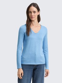 Lichtblauwe lange mouw V-hals top van zachte stof, aansluitende stijl, met een gladde textuur; gecombineerd met denim jeans.
