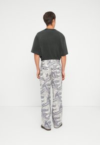 Short-sleeve dark gray t-shirt paired with light gray pants featuring a swirling black and white pattern, with visible back pockets.