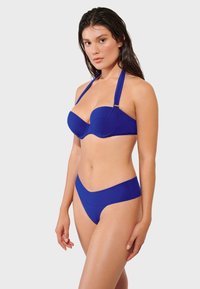 Modré bikiny so bezramenným vrchom s drôtikmi a s krčnou šnúrkou, v kombinácii s vysokými spodkami. Hladký povrch, jednofarebný.