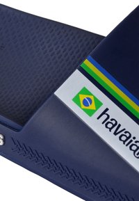 Navy rubber flip-flops met een gestructureerde voetbed, voorzien van een logo en een Braziliaanse vlagafbeelding op de band, geaccentueerd met groene en blauwe strepen.
