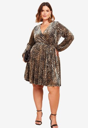 Leopard print wrap dress in shimmer fabric, featuring long sleeves, a deep V-neck, a belted waist, and pleated skirt. Black strappy sandals.