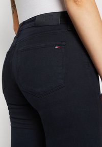 Jeans scuri con un design aderente. Presentano un'etichetta in pelle, tasche posteriori e un piccolo accento del logo tricolore vicino alla tasca.