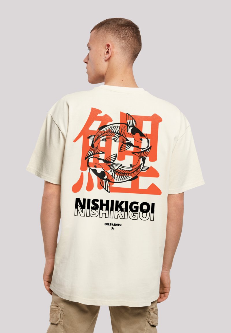 Cream-colored oversized t-shirt featuring a large black and orange koi fish graphic and Japanese text on the back. Smooth cotton texture.