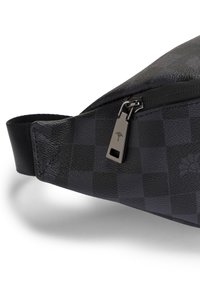 Zwarte nylon tas met ruitpatroon en een gladde textuur, voorzien van een ritssluiting en een zilverkleurige ritstrekker met logo detail.