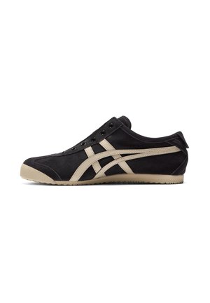 Schwarzer Sneaker mit beigen Streifen, Gummisohle und Ösen, von der Seite auf weißem Hintergrund dargestellt.