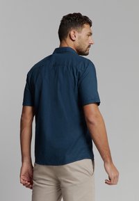 Korte mouwen shirt van donkerblauwe stof, met een button-down kraag, voorzien van een rugnaad met kleine knoopdetails, een gladde textuur en een casual pasvorm.