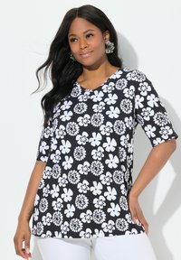 Top de patrón floral en blanco y negro con escote en V, mangas cortas y corte holgado. La tela tiene una textura suave.