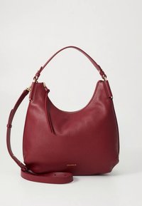 Burgundy leather handbag with a curved shape, detachable shoulder strap, and subtle gold hardware. Textured surface with a zip closure.