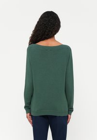 Green oversized sweater with long sleeves, scoop neckline, and ribbed accents at the collar and hem. Soft texture and relaxed fit.