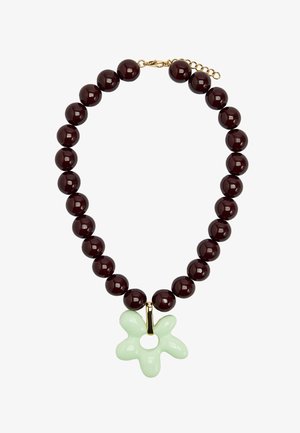 Naszyjnik z okrągłych, ciemnobrązowych koralików z jasnopistacjowym, abstrakcyjnym wisiorkiem w kształcie kwiatu oraz złotym zapięciem.