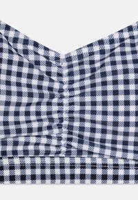 Marineblå och vit rutig bralette med V-formad halsringning, samlad textur och sömnad detaljer längs sömmarna och nederkanten.