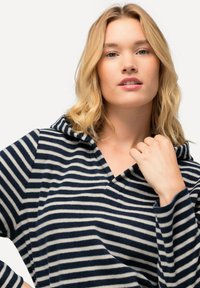 Sudadera con capucha en rayas azul marino y crema, hecha de una tela suave con un ajuste relajado, que presenta un escote en V y mangas largas.