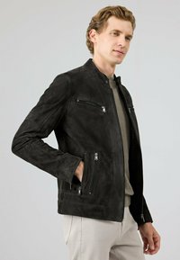 Zwarte suède jas met een staande kraag, ritssluiting aan de voorkant en zijzakken, gestructureerde afwerking, slim ontwerp en minimalistische hardwareaccenten.