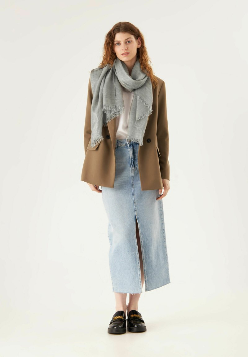 Bordeaux blazer, grijze sjaal, witte blouse, high-waisted denim rok met een voorknip, en zwarte instappers met gouden accenten.