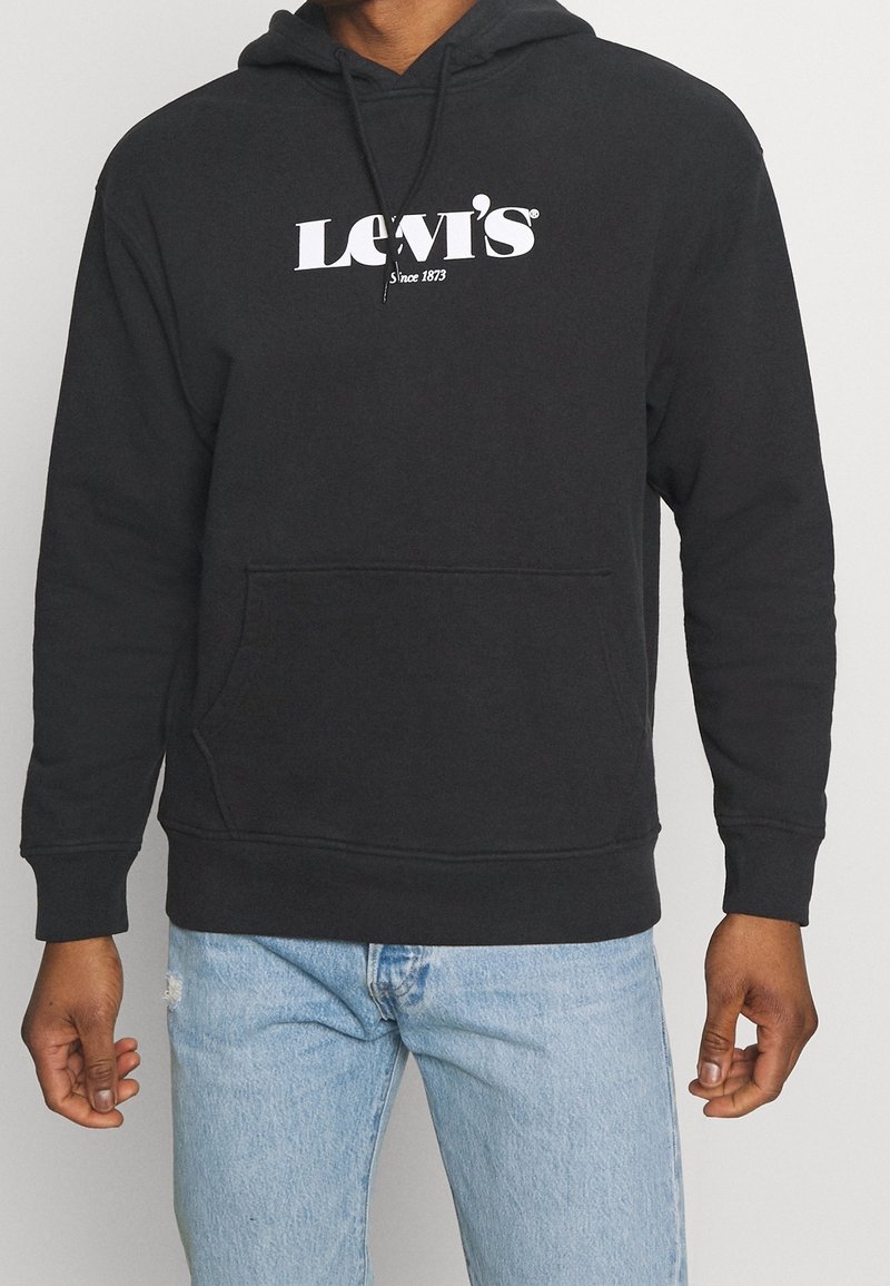 Sweat à capuche noir en tissu doux, avec une poche kangourou et le logo Levi's blanc sur la poitrine. Coupe décontractée avec des poignets côtelés.