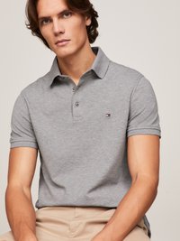 Grå polo shirt med klassisk krave, korte ærmer og et lille stribet logo på venstre bryst. Glat bomuldsstruktur, skræddersyet pasform.