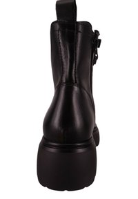 Botín de cuero negro con superficie texturizada, cierre lateral con cremallera y suela negra gruesa. Cuenta con una lengüeta en el talón para facilitar su colocación.