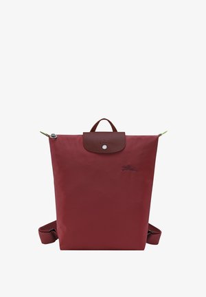 Red nylon backpack with a brown leather flap, top handle, and adjustable shoulder straps. Features silver hardware and embossed logo.