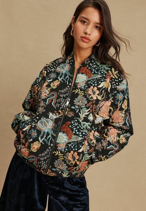 Schwarze Bomberjacke mit bunten Blumen- und Tierstickereien, Reißverschluss und gerippten Bündchen. Verfügt über eine lockere Passform und eine weiche Textur.