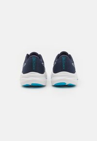 Scarpe da ginnastica blu navy con tomaia in rete, intersuola bianca con accenti blu e suola in gomma testurizzata. La vista posteriore evidenzia il marchio.