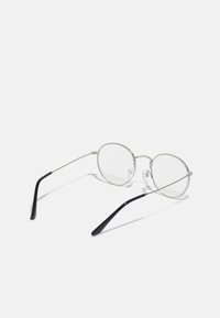 Ochelari rotunzi din metal cu rame subțiri argintii, lentile transparente și vârfuri negre pentru brate. Dispun de cleme pentru nas ajustabile pentru confort.