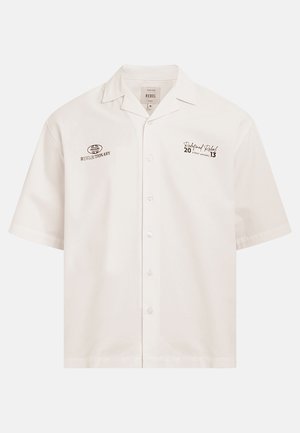 Weißes Kurzarm-Hemd mit Knöpfen und Kragen, mit Textlogos „Revolutionary Pressure" auf der linken Brust und „Redefined Rebel Street Apparel" auf der rechten Brust.