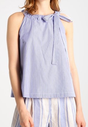 Haut sans manches bleu et blanc à rayures verticales avec col à volants et nœud noué sur une épaule, porté avec un pantalon à rayures bleu et blanc.