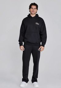 Black hooded sweatshirt with front pocket, paired with black sweatpants. Both have a soft texture and a minimalist design featuring a logo.