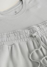 Lys grå ribbet stof loungewear-sæt med rund halsudskæring, elastisk talje med snøre og blød tekstur med samlede detaljer.