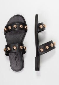 Black slide sandals with two wide straps featuring bronze studs. Textured leather material with a flat sole and soft interior lining.