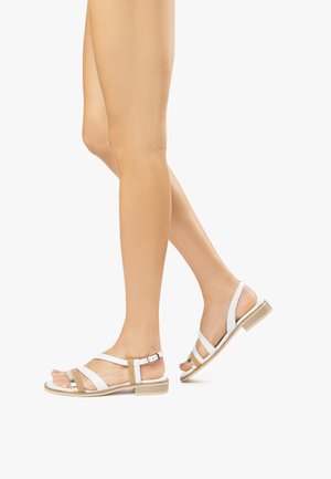 Sandali bianchi in pelle con accenti beige, suola piatta, cinturino alla caviglia regolabile e più sottili cinghie che attraversano il piede.