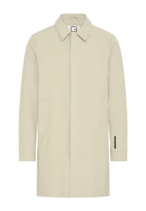 Béžový dlouhý kabát s dlouhými rukávy, límcem, předními kapsami a rovný střihem. Má minimální prošití a štítek na levém rukávu.