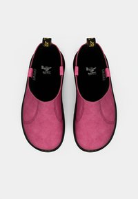 Pink suede slip-on shoes with a rounded toe, featuring a black rubber sole and pull tabs on each side for easy wear.
